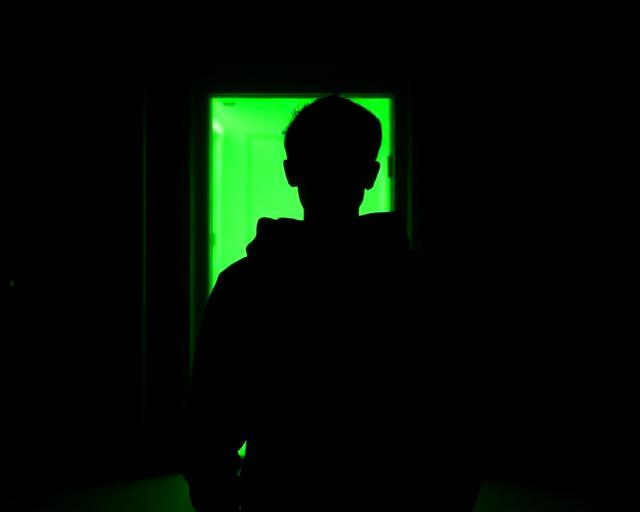 Person facing one glowing lime door among many